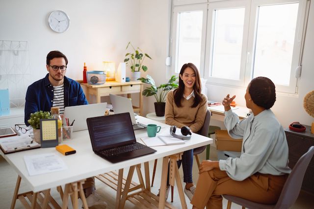 Three employees, a man and two women, work on a project together.