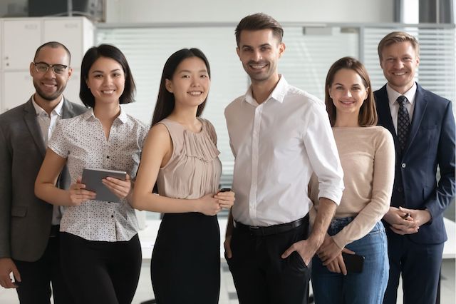 A group of six diverse employees pose smiling