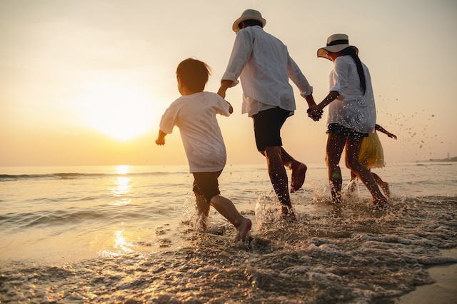 A happy Asian family plays at the beach