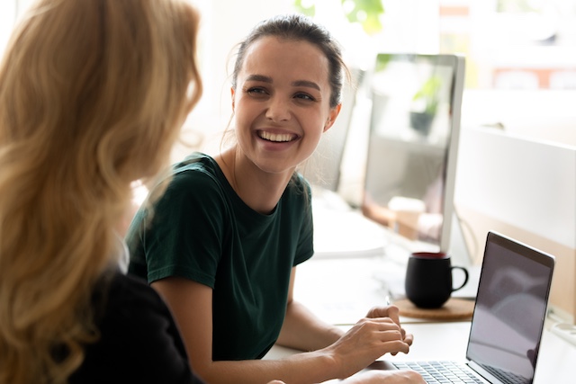 A female employee helps a female intern in an office