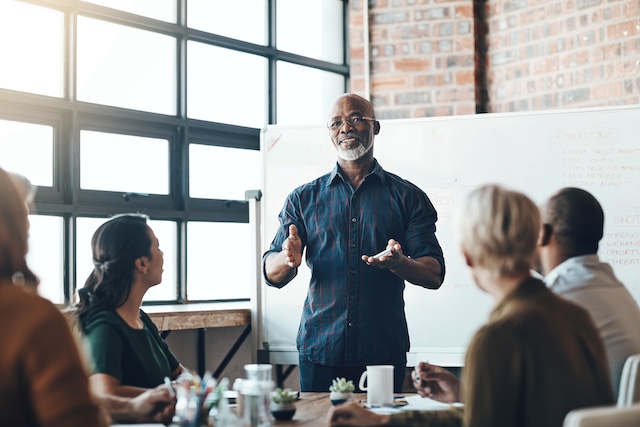 A young Black woman leads her team in a project meeting
