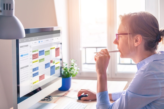A woman looks at her work calendar on her computer monitor