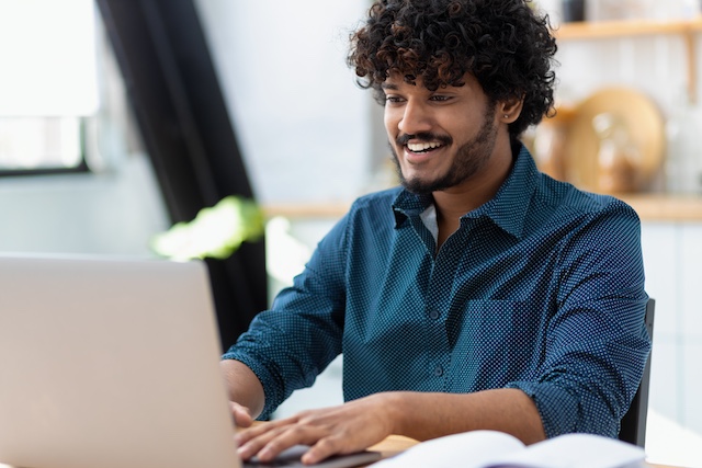 Young Indian employee smiles as he completes his employee engagement survey