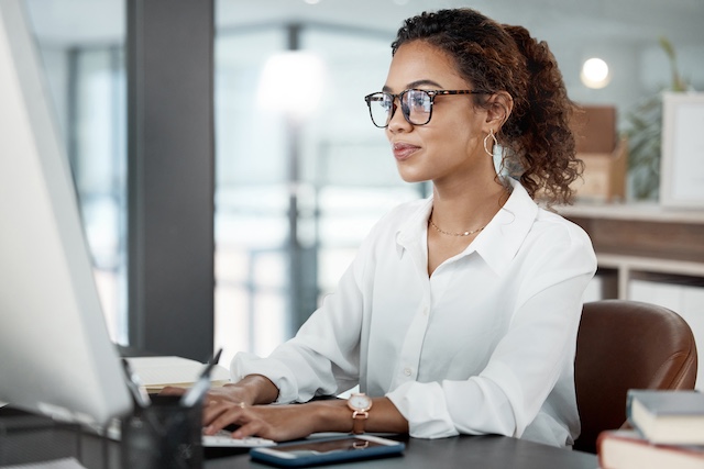 Woman wearing glasses concentrates as she works at her computer at work