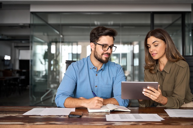 Female manager helps her male employee using a tablet
