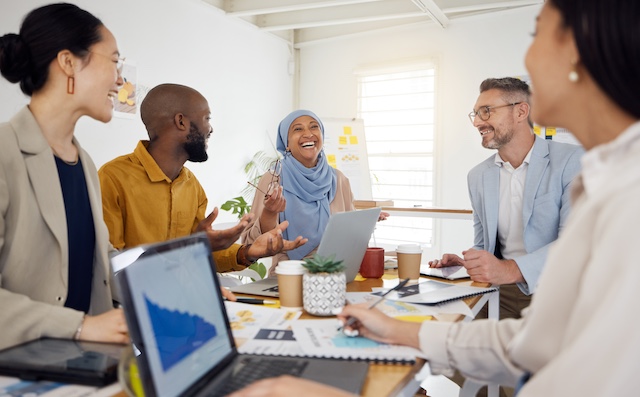 A group of diverse employees work on a project at a conference table