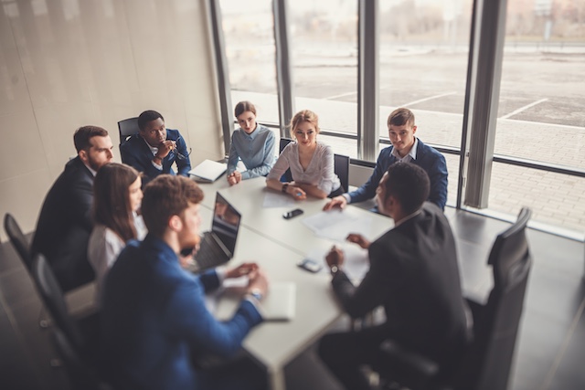 A manager leads his diverse team in a discussion at a conference table
