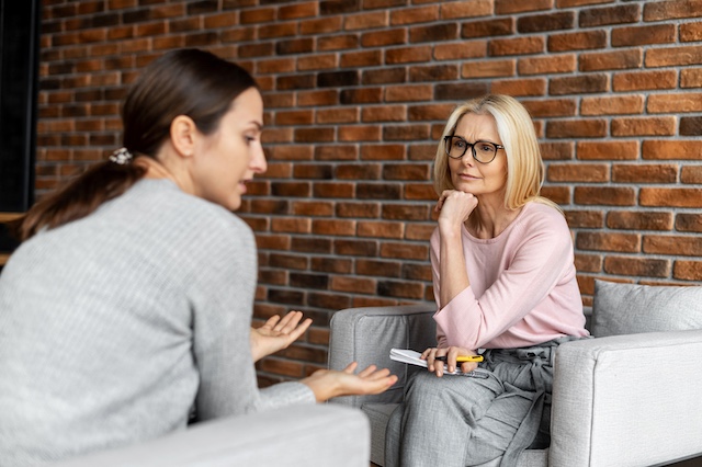 A mature female employee uses active listening skills while a younger female colleague discusses an issue