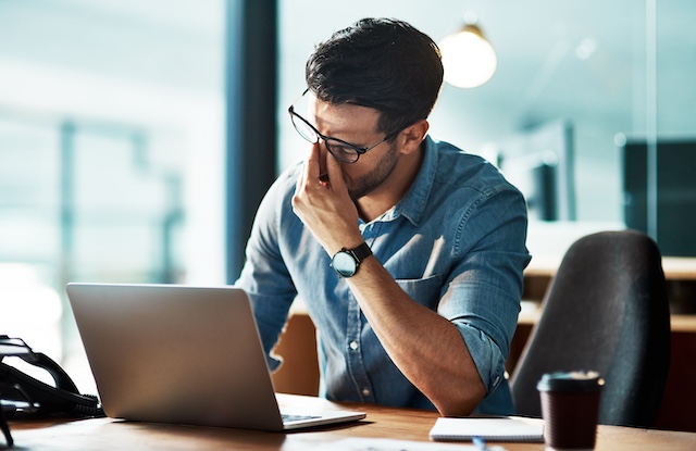 An overworked employee shows signs of burnout while working at his desk