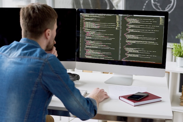 A male programmer concentrates while working at his monitor