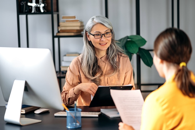 A mature female Asian manager meets with her younger female employee in her office