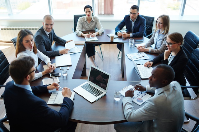 A group of executives meet around a table engaged in serious discussion