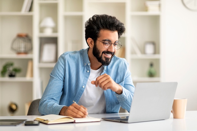 Bearded Indian man wearing glasses meets with an outplacement coach virtually from home