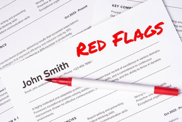 A pen sits on top of a resume with the words